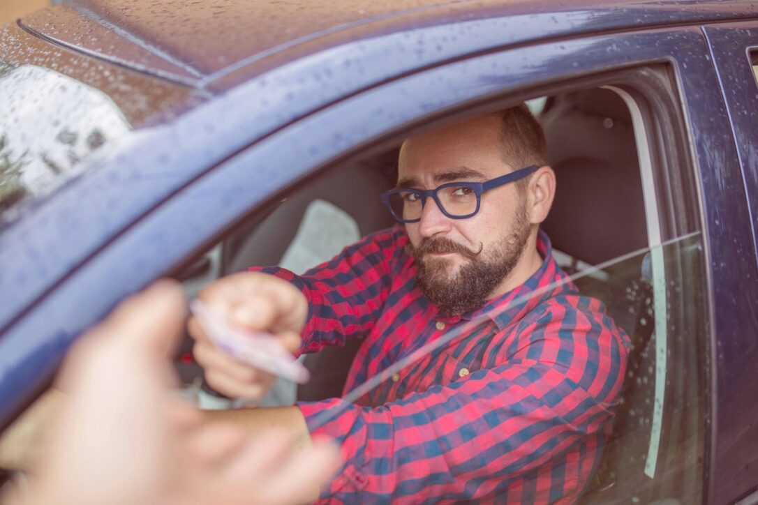 Photo of a driver handing his license to a police officer.