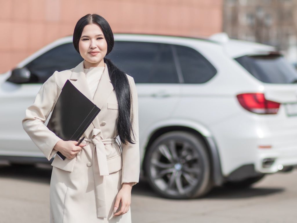 A woman standing by a parked car.