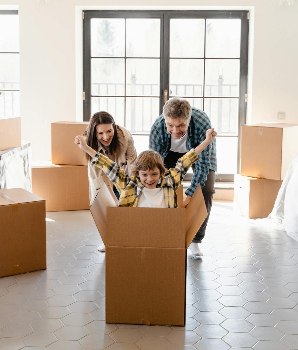 A child playing in a large cardboard box. His parents are also playing along.